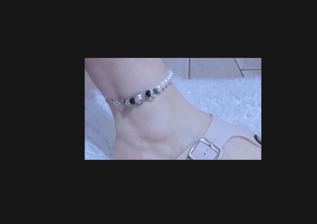 Ce bracelet de cheville élégant associe des perles blanches métallisées, une fleur en cristal et une chaîne résistante en acier inoxydable 