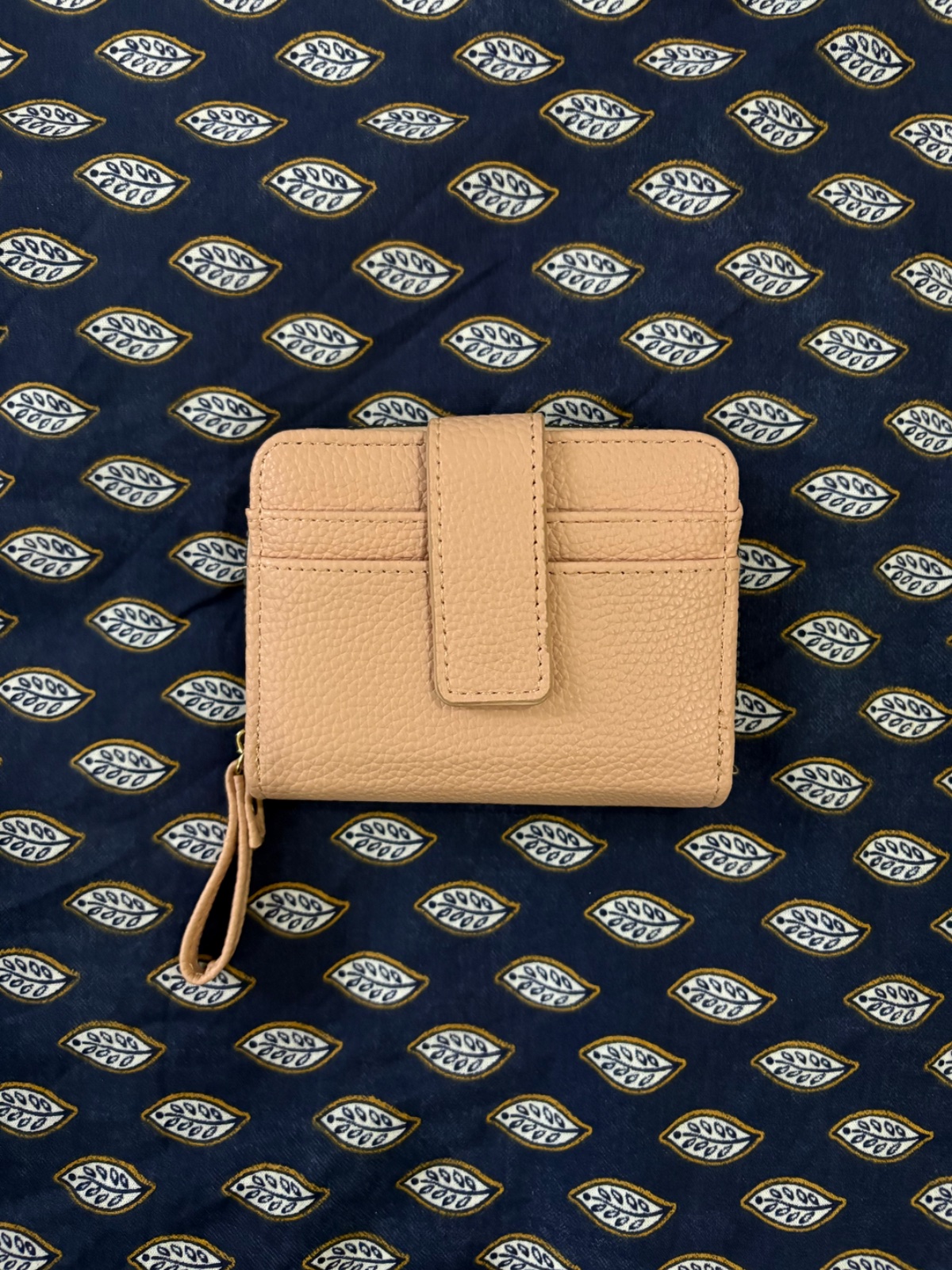 Portefeuille rosé avec  un design compact et pratique doté d'une patte à pression sur le devant ainsi que d'une dragonne zippée assortie