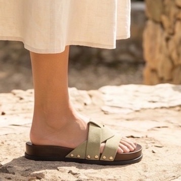 Mules beige à brides croisées ornées de petits clous dorés, montée sur une semelle confortable à effet bois
