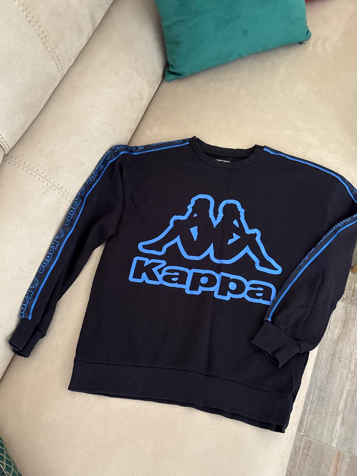 Sweat-shirt à col rond noir avec un grand logo Kappa bleu fluo sur la poitrine et des bandes assorties sur les manches ressemble au modèle Kappa Sweat RN, Logo Airivit Blue/Black