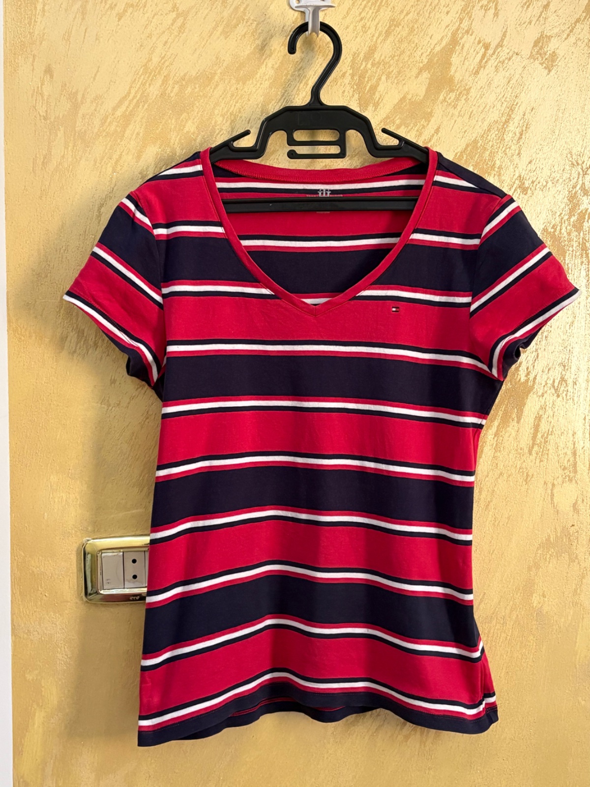 T-shirt Tommy Hilfiger arbore un motif rayé classique en rouge, bleu marine et blanc avec un col en V distinctif