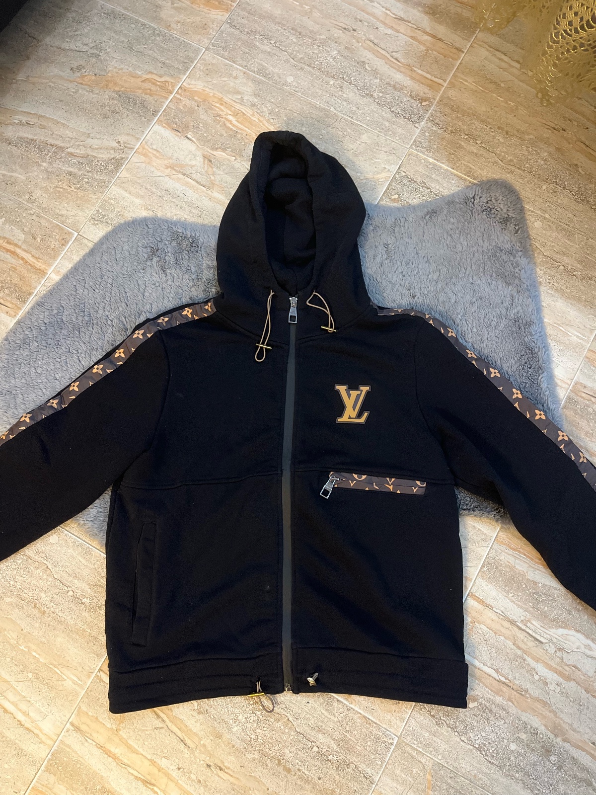 Veste à capuche zippé Louis Vuitton de couleur noire, orné de bandes latérales et d'une poche poitrine avec le monogramme LV emblématique de la marque
