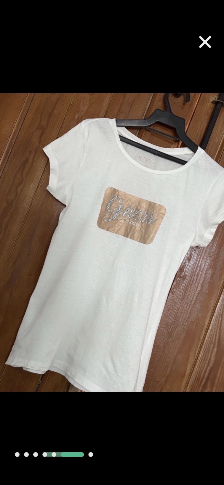 T-shirt blanc Guess présente un logo "Guess Los Angeles" orné de strass sur un patch de couleur bronze