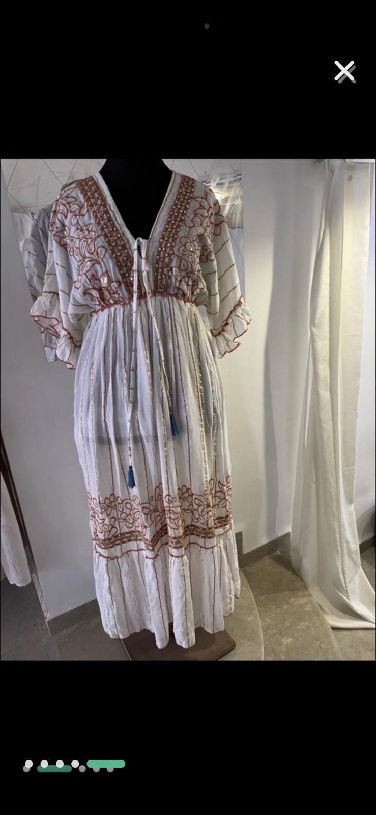 Robe blanche ornée de broderies dorées et rouges et de pompons bleus