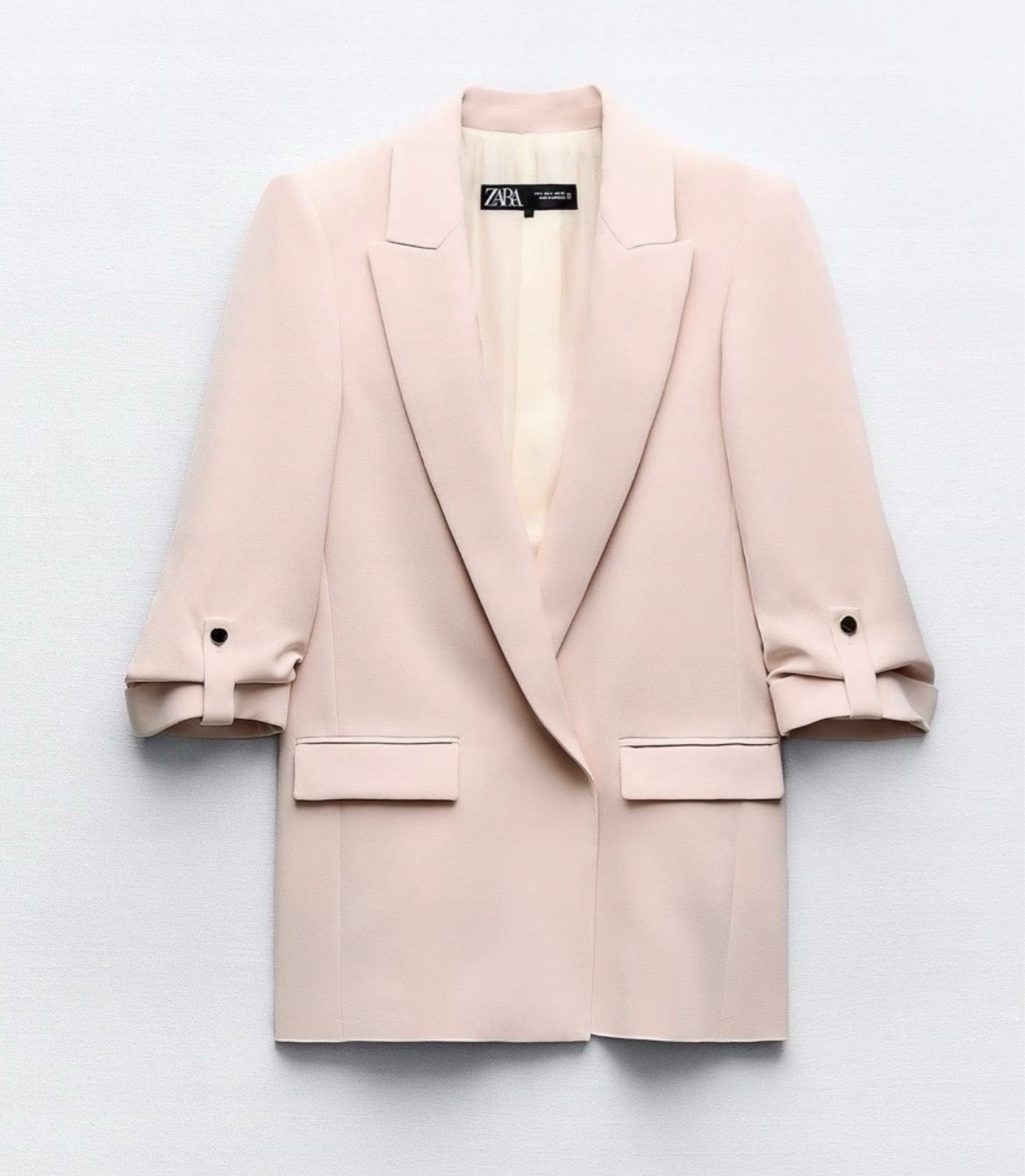 Blazer Zara Basic rose pâle avec des manches retroussées fixées par un bouton doré
