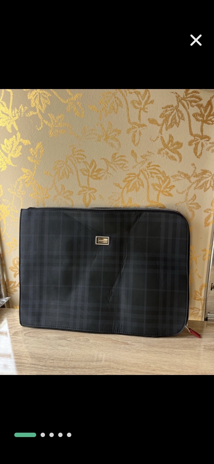 Pochette pour ordinateur portable ou une pochette de la marque Burberry, caractérisée par son motif à carreaux distinctif et son logo en métal sur le devant