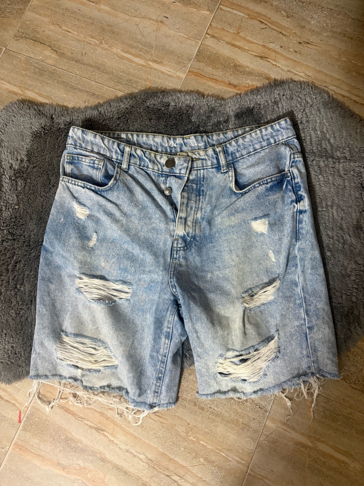 Short en jean bleu clair caractérisé par une coupe décontractée et des détails déchirés