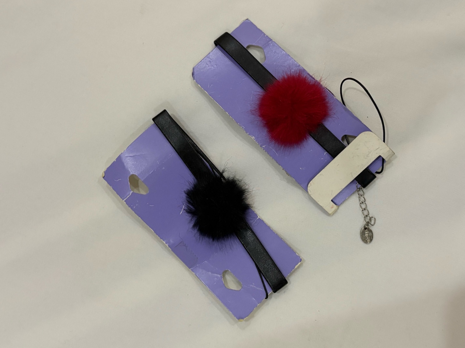Deux colliers ras-de-cou avec des pompons en fausse fourrure rouge et noire en similicuir