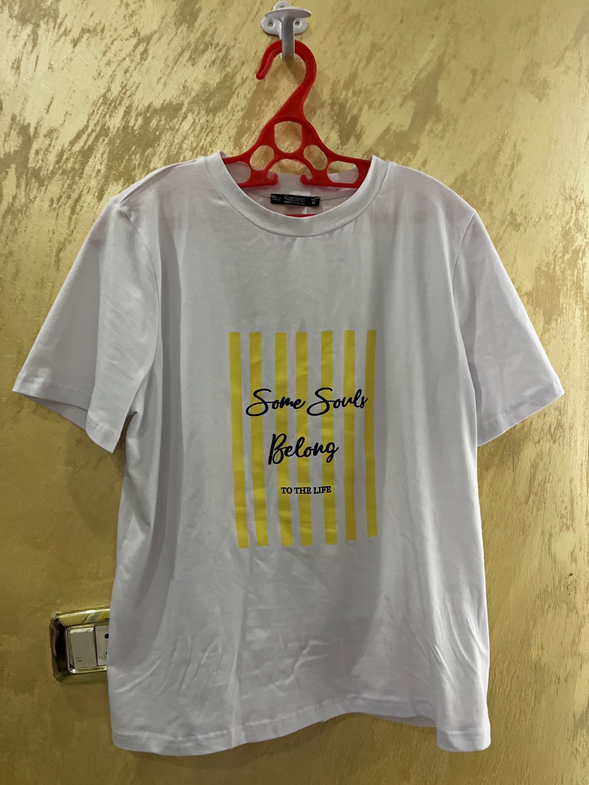 T-shirt Kastelo blanc en coton présente un motif graphique central sur fond de rayures verticales jaunes avec l'inscription « Some Souls Belong to the Life 