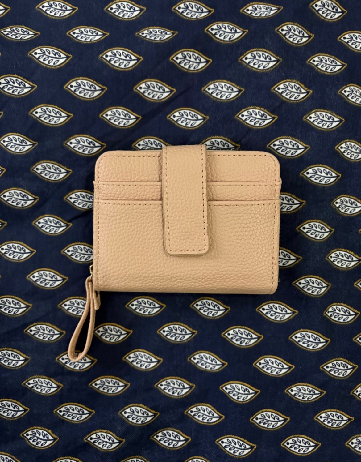 Portefeuille rosé avec un design compact et pratique doté d'une patte à pression sur le devant ainsi que d'une dragonne zippée assortie