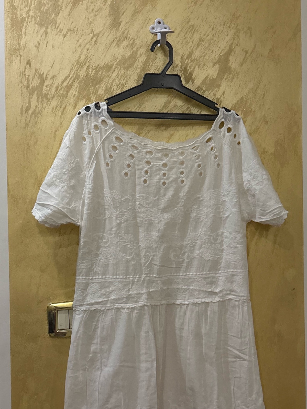 Robe blanche mi-longue en broderie anglaise présente un col rond évasé orné de détails ajourés