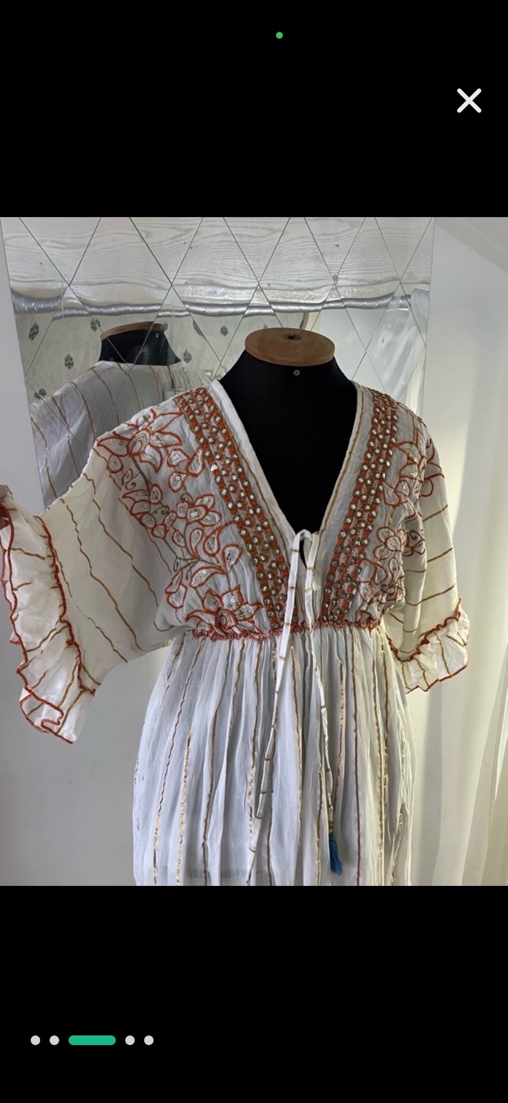 Robe blanche ornée de broderies dorées et rouges et de pompons bleus