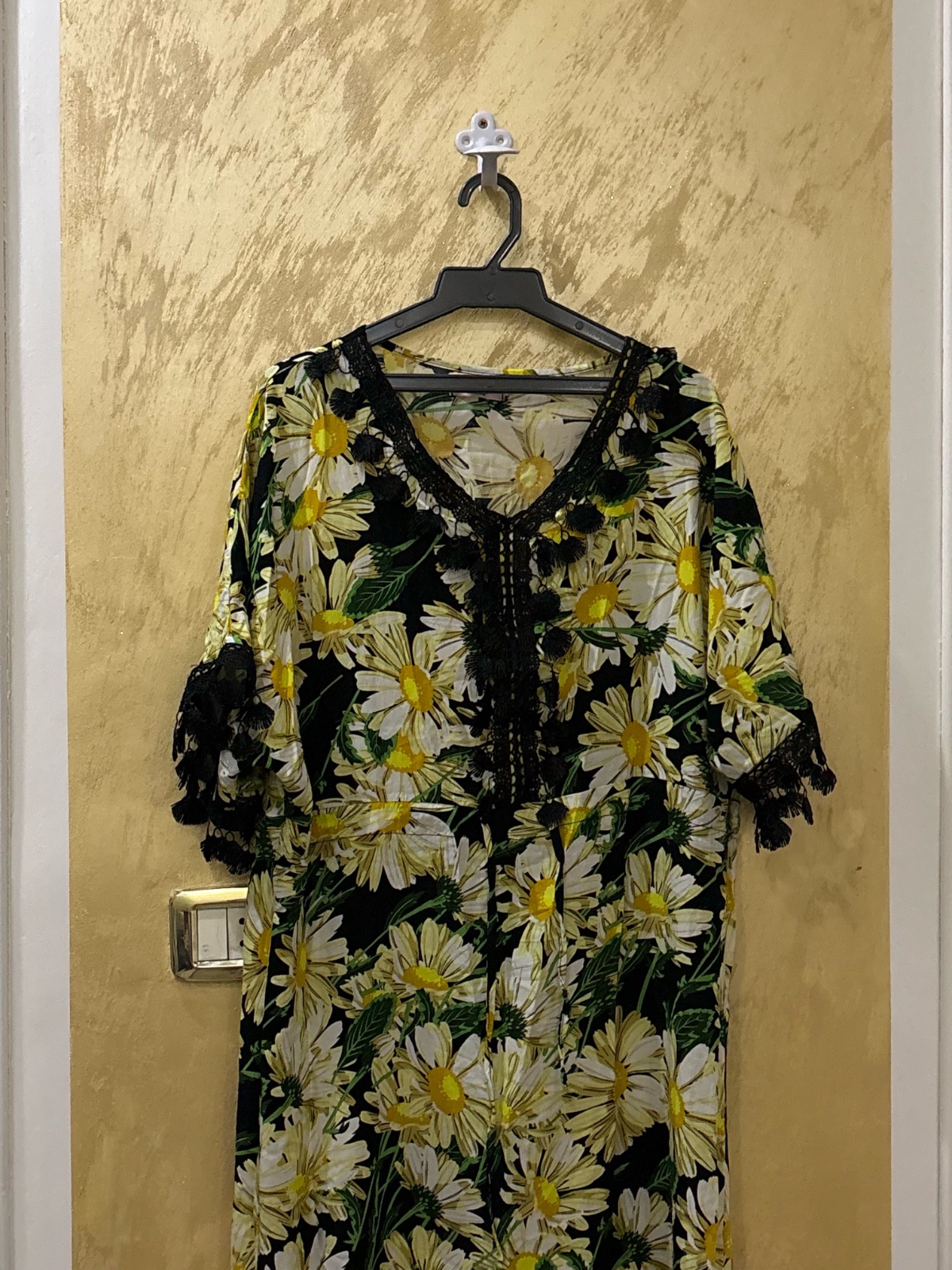 Robe jeba ornée d'un motif floral de marguerites jaunes sur fond noir et comporte des détails en dentelle noire au col et aux manches
