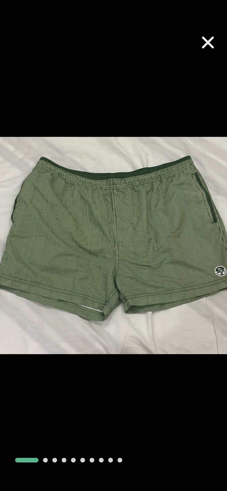 Short de bain vert rayé présente une taille élastique confortable et un petit logo circulaire sur la jambe gauche