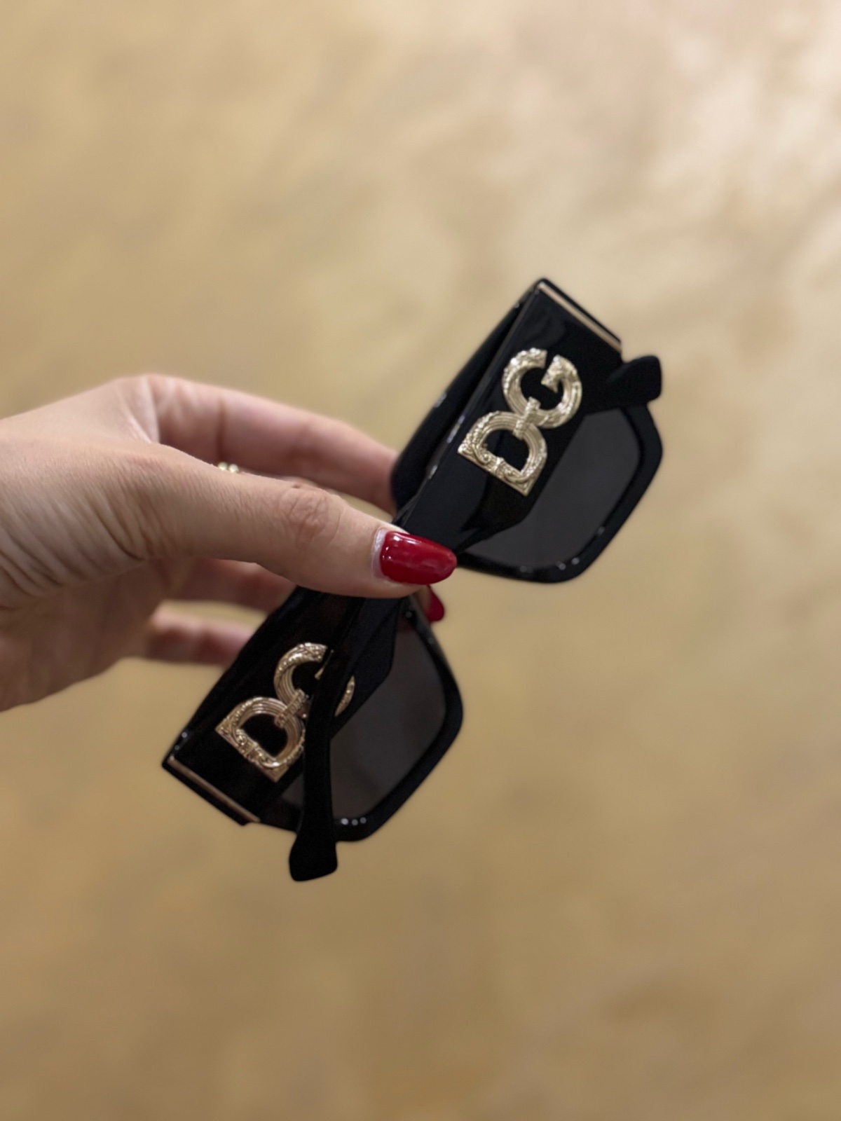 Lunettes de soleil  caractérisées par une monture rectangulaire noire et un logo DG doré imposant sur les branches