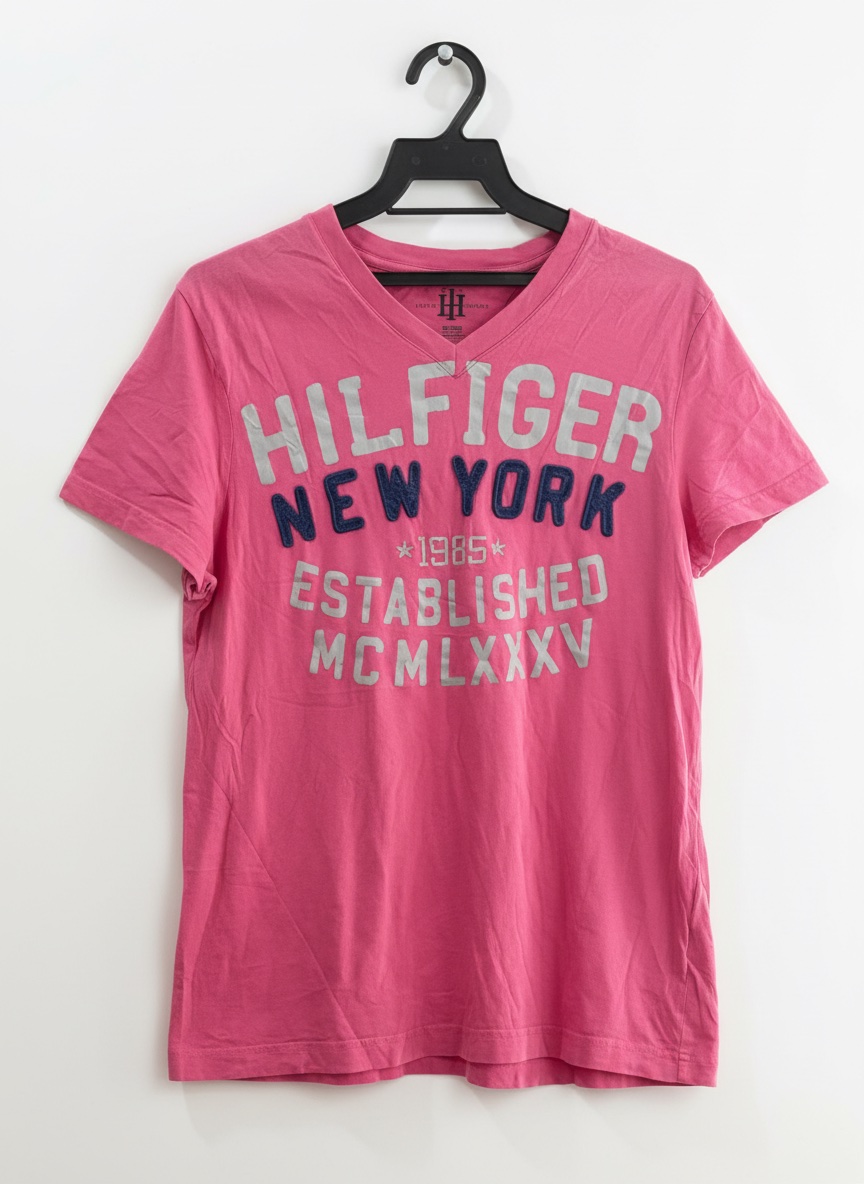 T-shirt Tommy Hilfiger Denim rose à col en V présente un grand graphique imprimé "HILFIGER NEW YORK" sur la poitrine