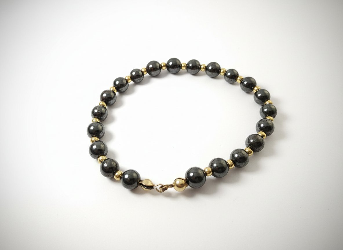 Très jolie bracelet de perles d'hématite gris foncé métallisé alternées avec de petites perles d'espacement dorées.  