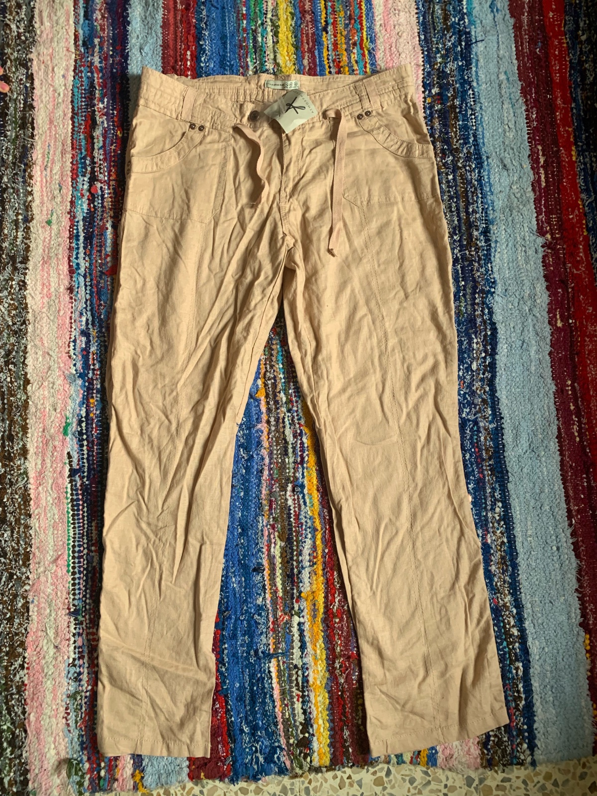 Pantalon beige de coupe droite, doté d'un cordon de serrage à la taille et de poches avant.