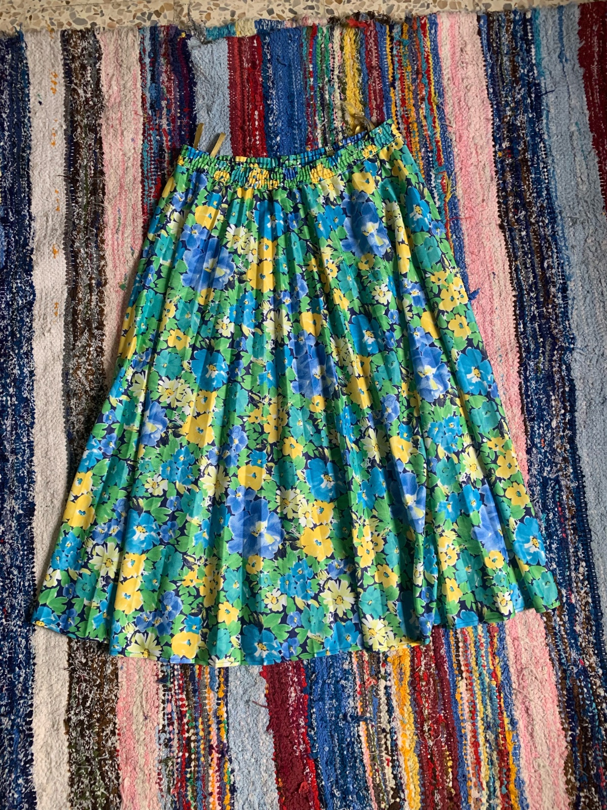 Jupe midi plissée taille haute mise en valeur par un imprimé floral multicolore aux nuances vibrantes de bleu, de vert et de jaune.