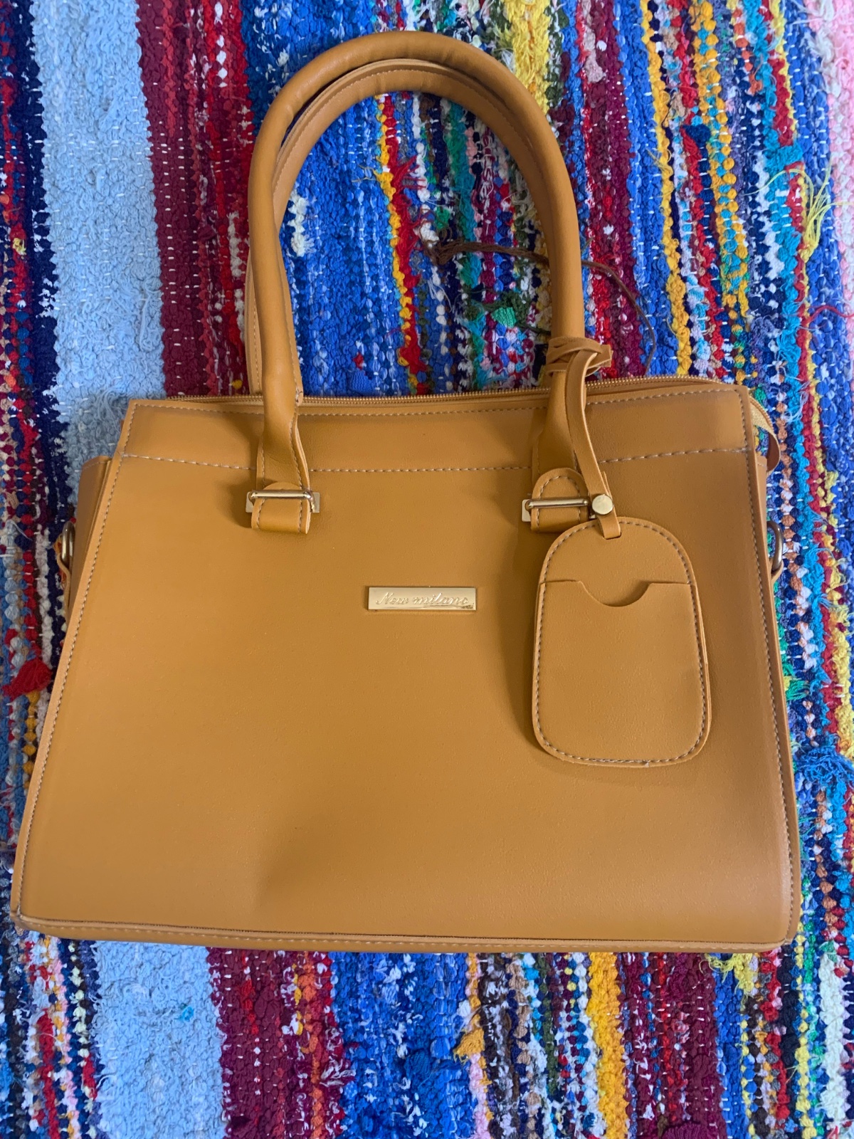 Sac à main structuré en similicuir de couleur jaune moutarde avec des poignées rigides et un petit porte-cartes suspendu.