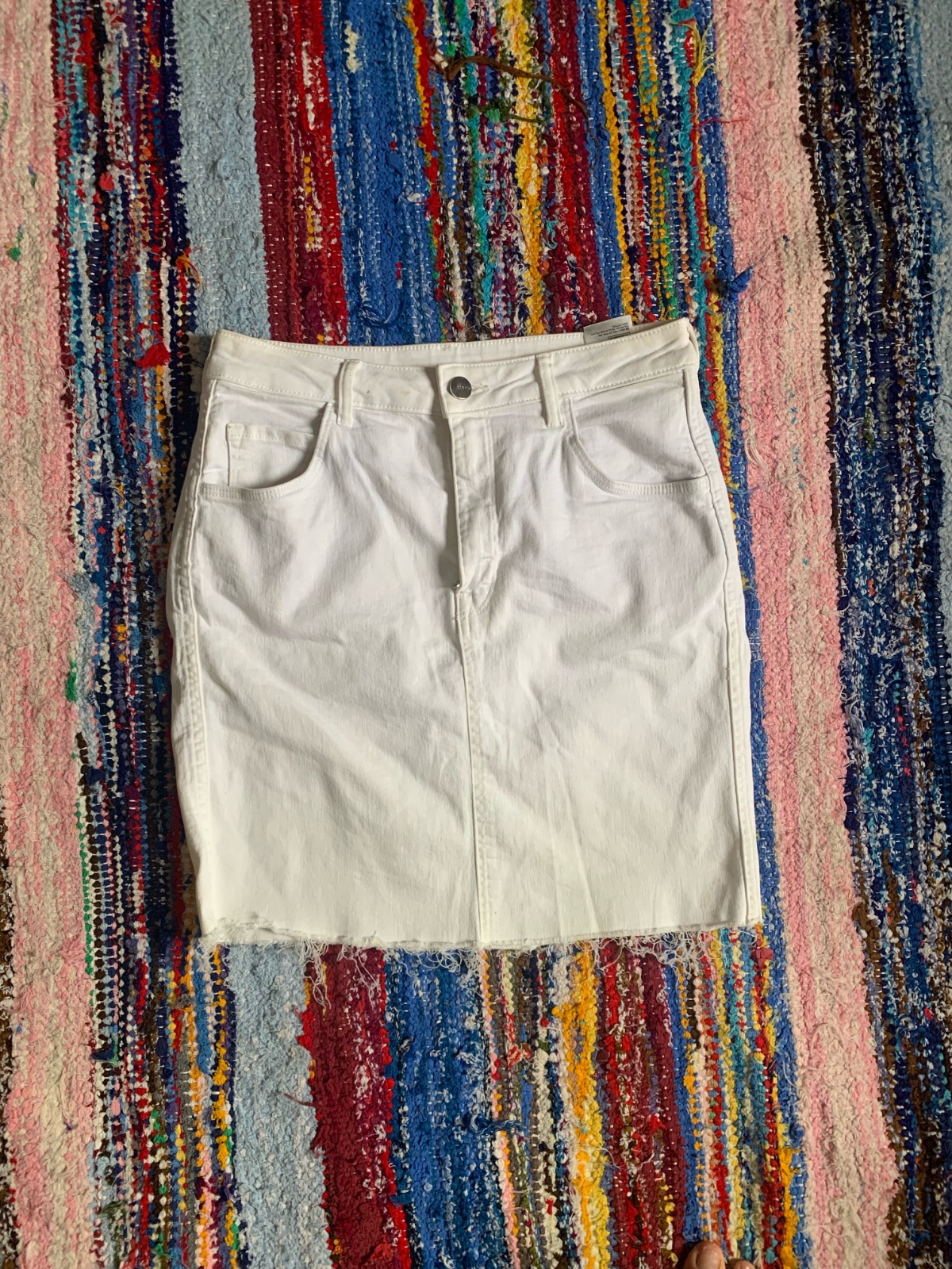 Mini-jupe en denim blanc dotée d'un ourlet effiloché.