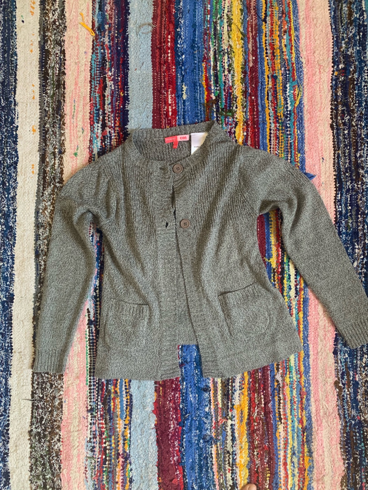 Cardigan en maille grise doté de poches plaquées à l'avant et de boutons assortis.