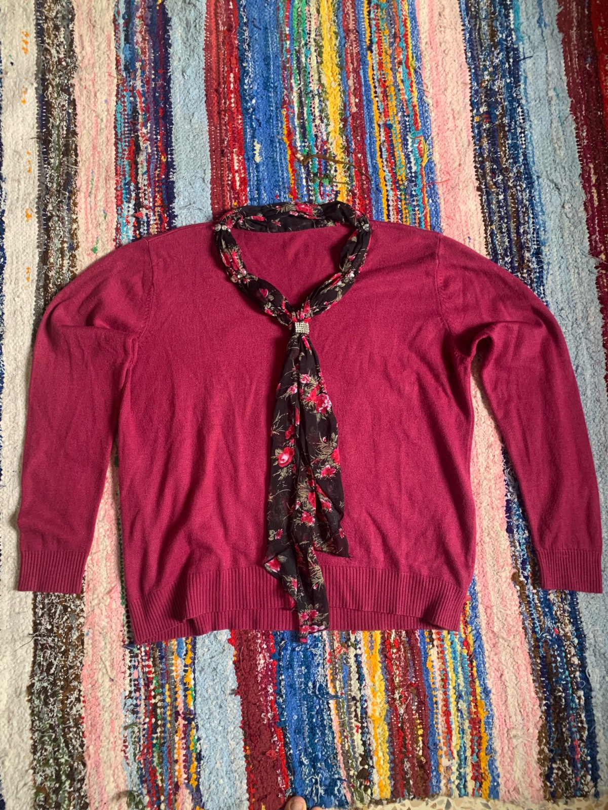 Pull en maille fuchsia à manches longues agrémenté d'un élégant col lavallière à motif floral.