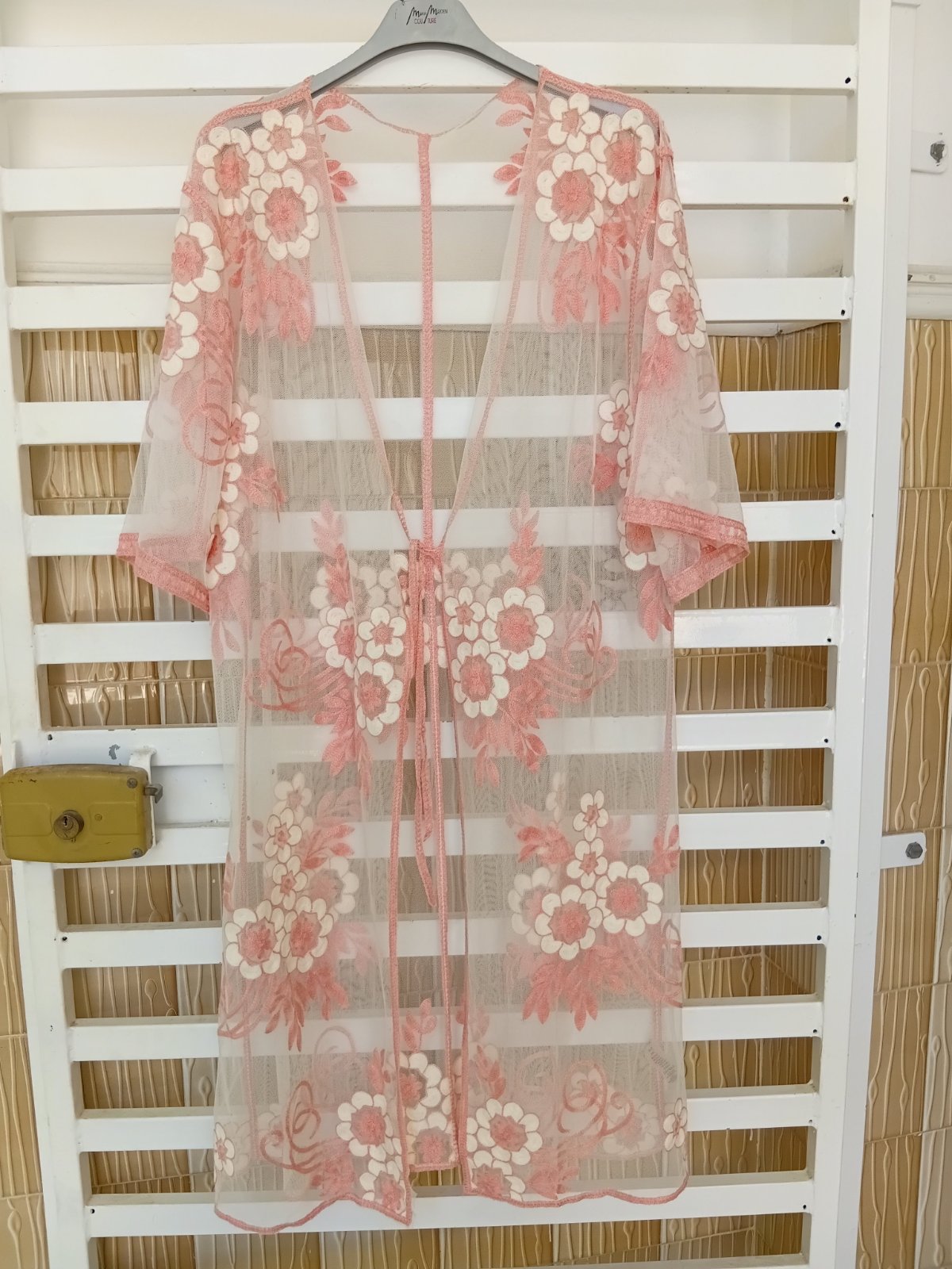 Kimono transparent en tulle rose avec broderies florales en relief. Léger et élégant, idéal pour l'été, la plage ou pour compléter une tenue chic.