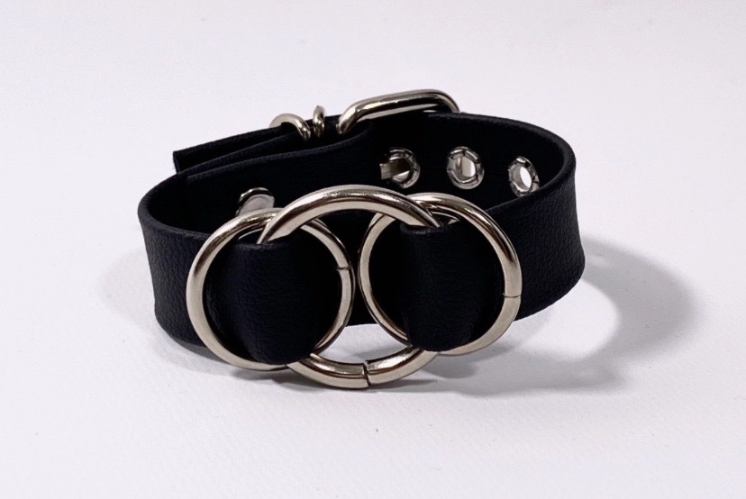 Black leather bracelet featuring polished interlocking metal O-rings and an adjustable buckle closure.