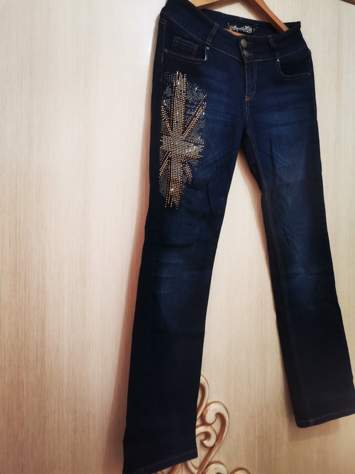  Pantalon jeans en denim bleu ornée  d'un motif en strass doré chic. 