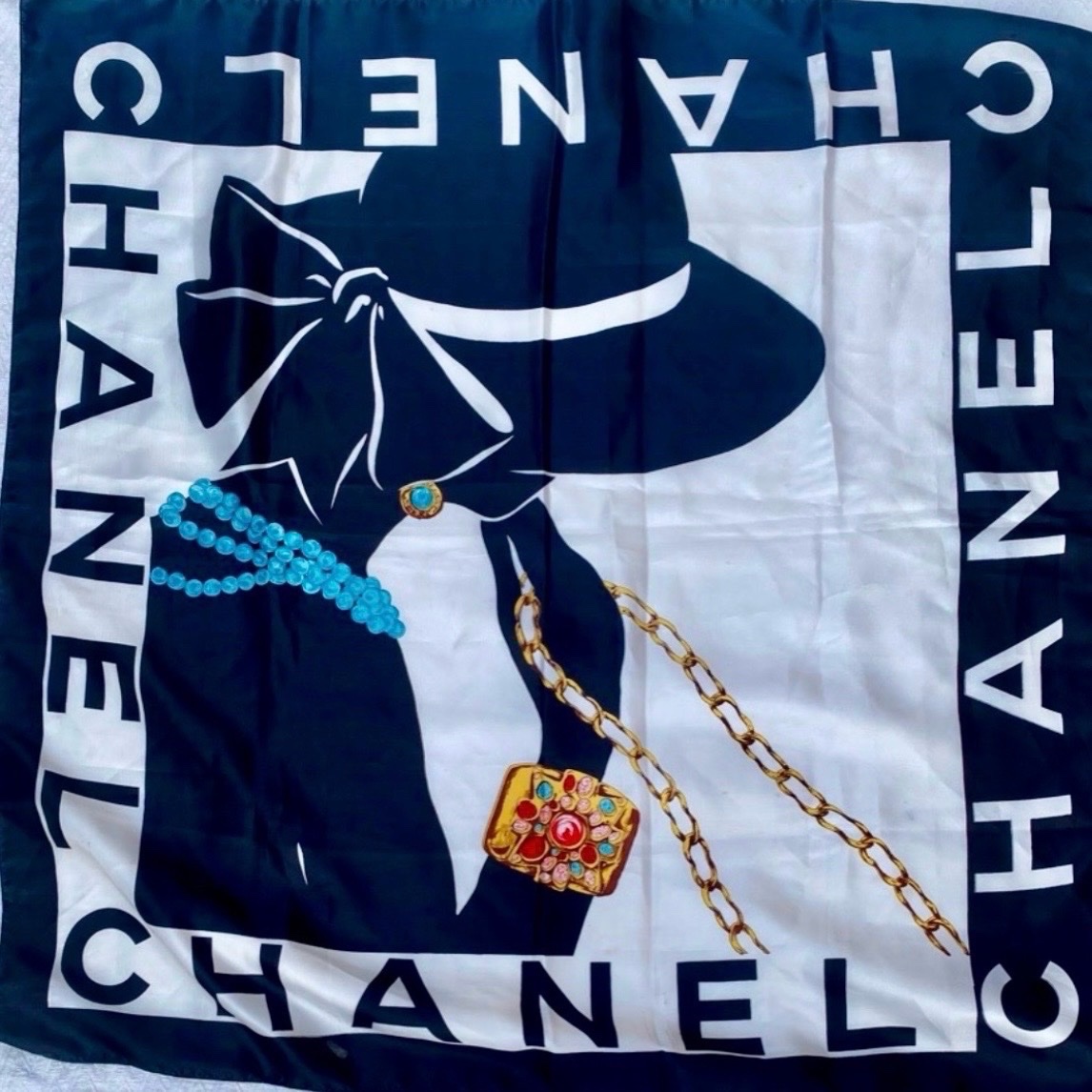 Ce carré Chanel noire et blanc arbore un motif emblématique de la silhouette de Coco Chanel avec un chapeau et des bijoux mouch authentique raw ama jadayd w ma7lh