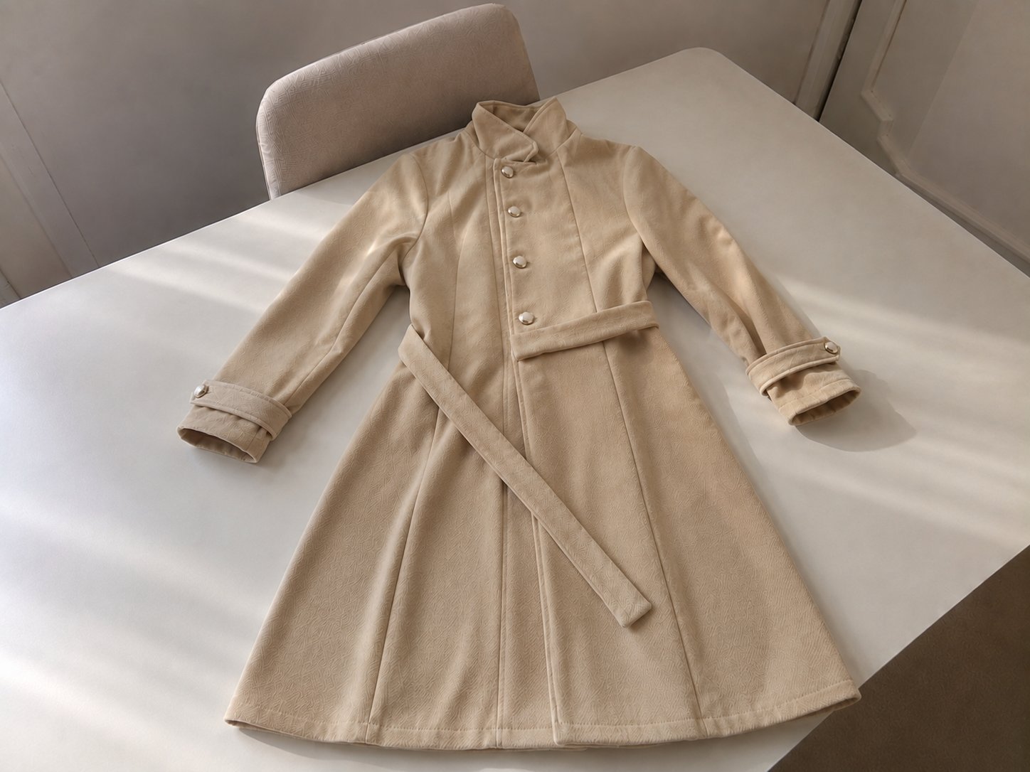 Manteau d’hiver féminin élégant de couleur beige clair, doté d’un col montant et d’une ceinture assortie à la taille