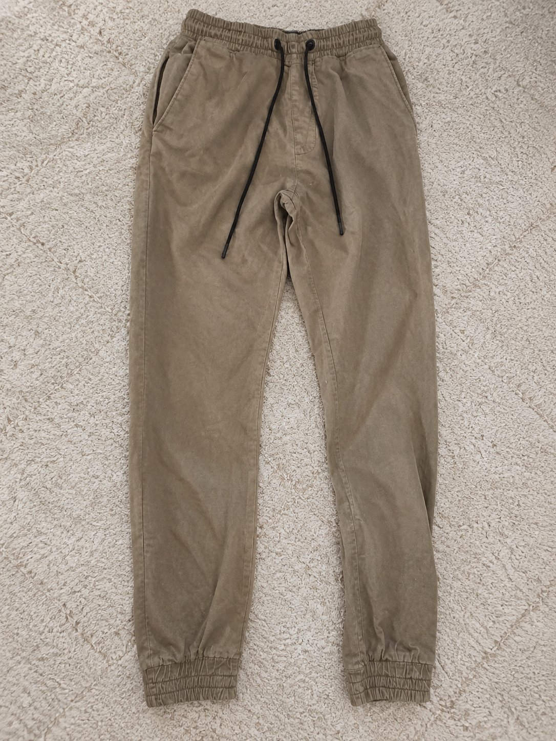 Pantalon cargo jogger beige kaki, avec poches latérales et taille élastique à cordon.