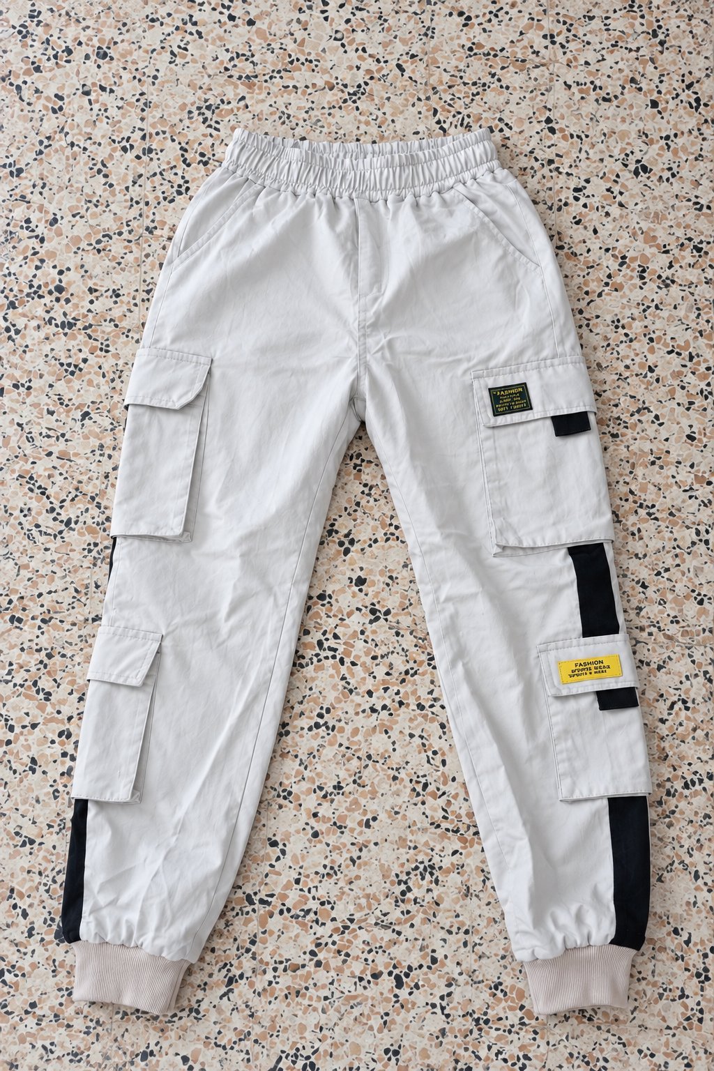 Pantalon cargo blanc, coupe jogging, avec poches multiples et détails noirs, confortable et tendance.