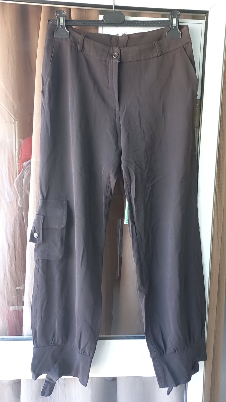 Pantalon cargo marron pour femmes, probablement en coton mélangé, avec une coupe ample, des poches latérales à rabat et des bas de jambes élastiqués. 