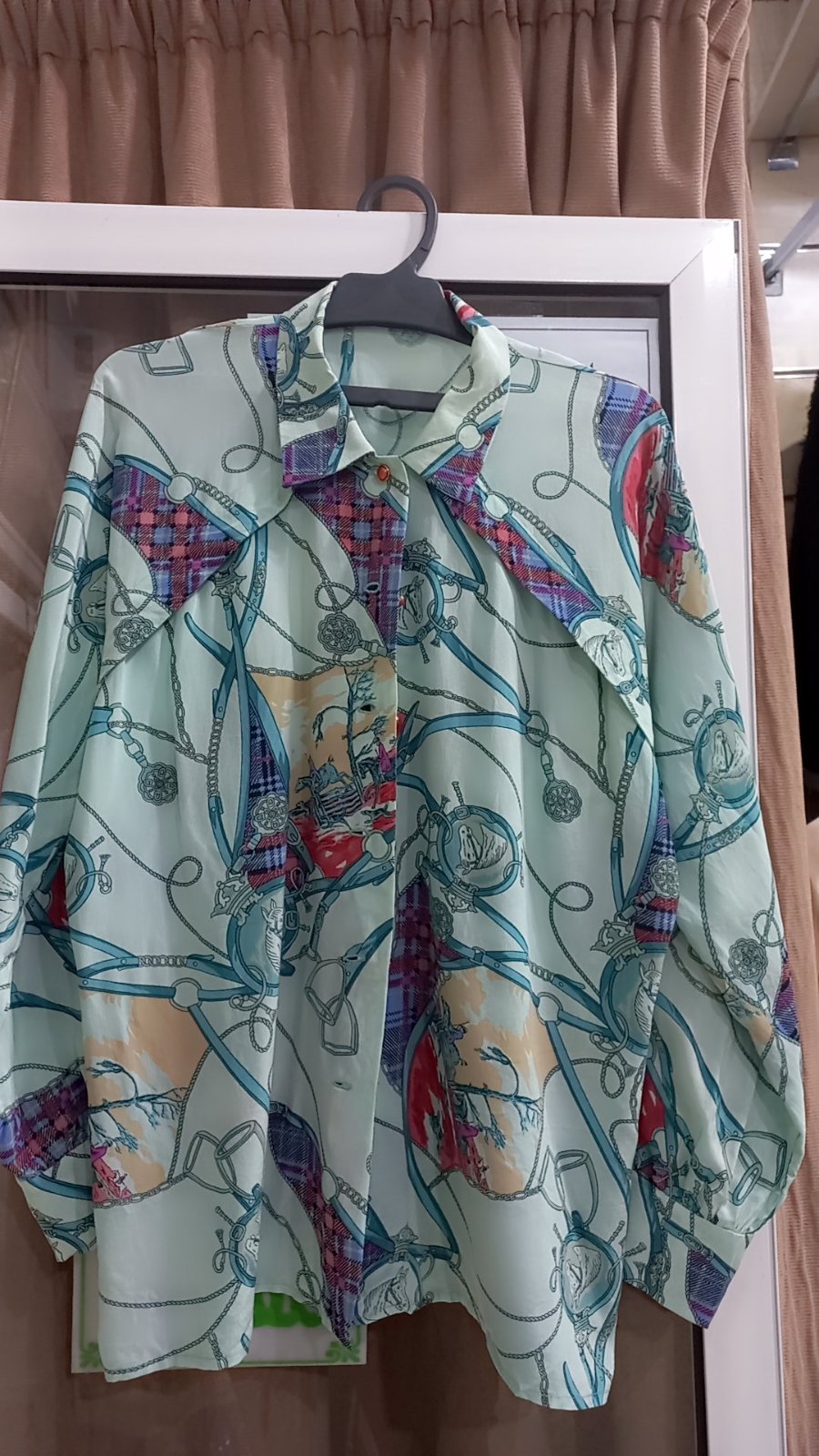 Une chemise à manches longues avec un motif imprimé de chaînes et de carreaux dans des tons pastel.