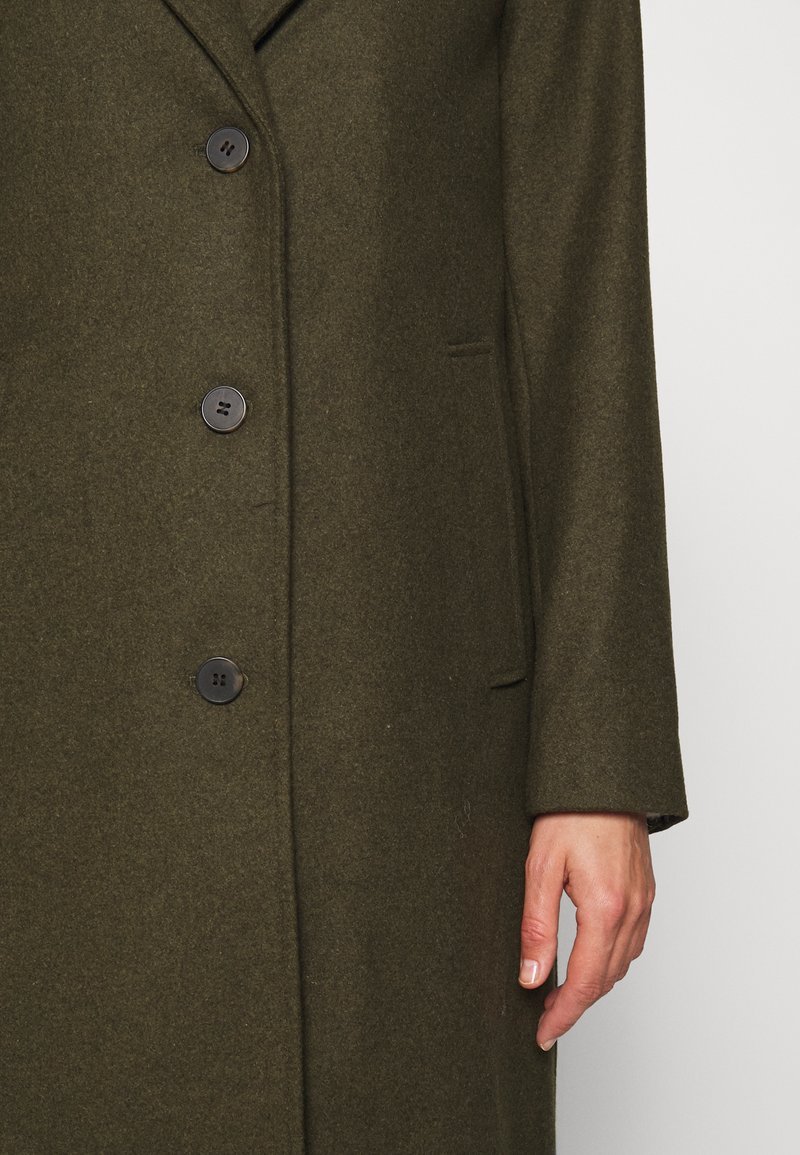 Manteau correspond au modèle SLFSASJA de la marque Selected Femme, caractérisé par sa couleur vert foncé et sa coupe classique. 