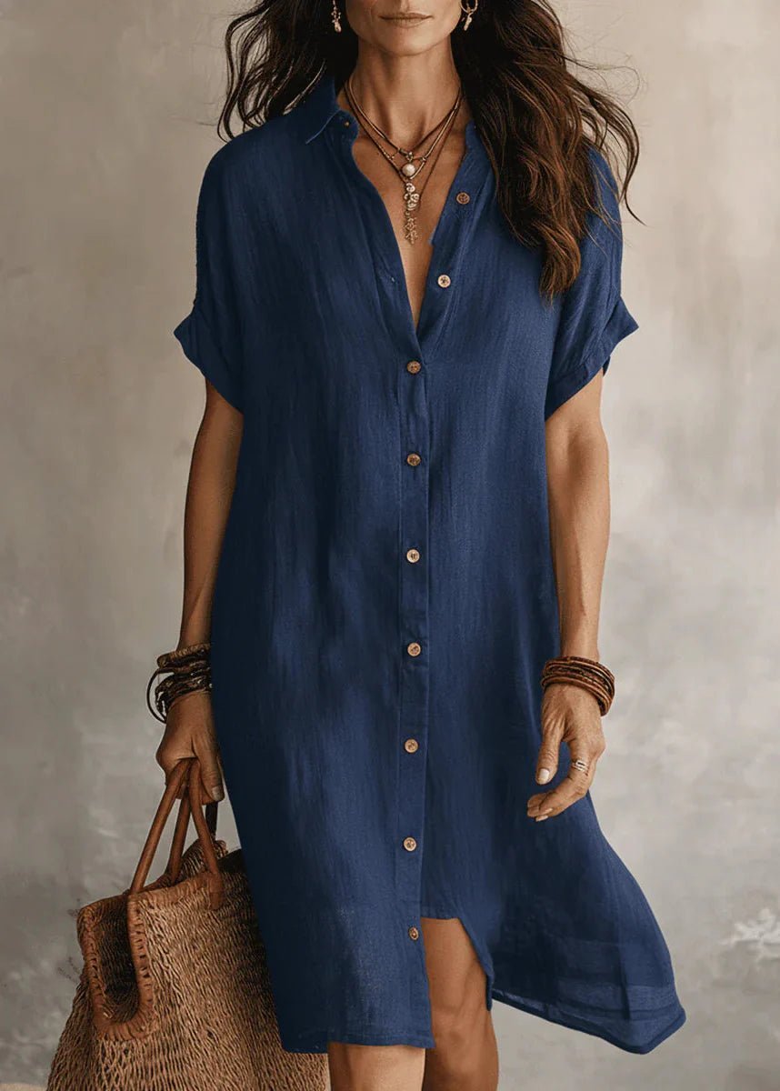 Robe-chemise en lin bleu marine se distingue par sa coupe décontractée à manches courtes, son col rond épuré et ses grands boutons blancs contrastants sur le devant et les deux poches poitrine.