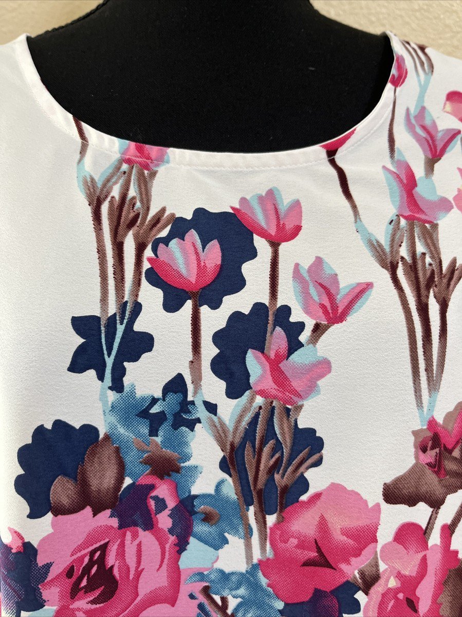 Haut sans manches pour femme arbore un motif floral coloré sur fond blanc. 
