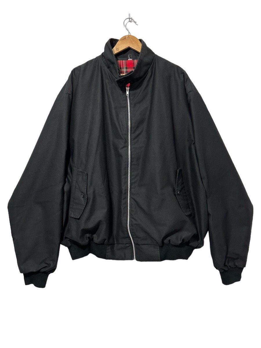 Blouson de type Harrington noir, reconnaissable à son col montant et à sa doublure intérieure à carreaux. 
