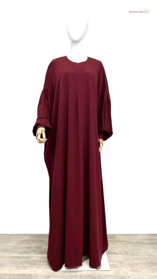 'une abaya ou d'un kaftan de couleur bordeaux, une robe longue et ample traditionnellement portée comme tenue modeste. 