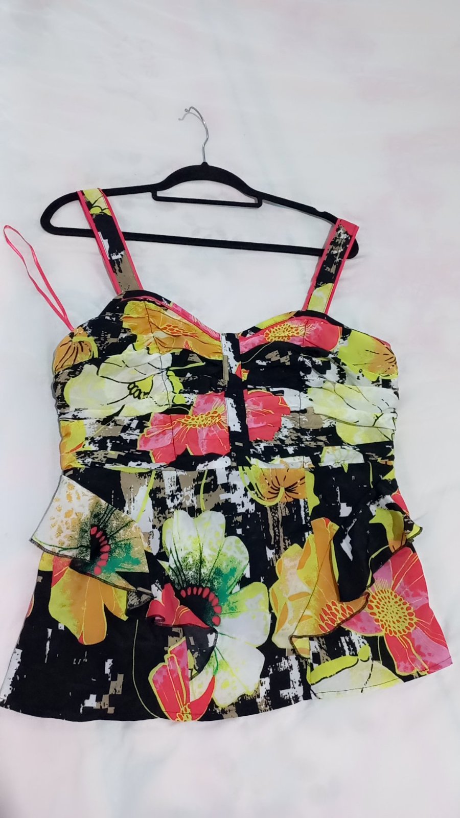 Vêtement est un haut de tankini ou de robe d'été de la marque Next, caractérisé par un imprimé floral multicolore éclatant sur fond noir et des bretelles ajustables.