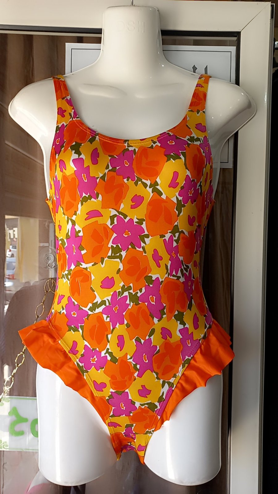 Un maillot de bain une pièce pour fille de la marque Kamyli Spor, caractérisé par son motif floral vif en orange et rose.