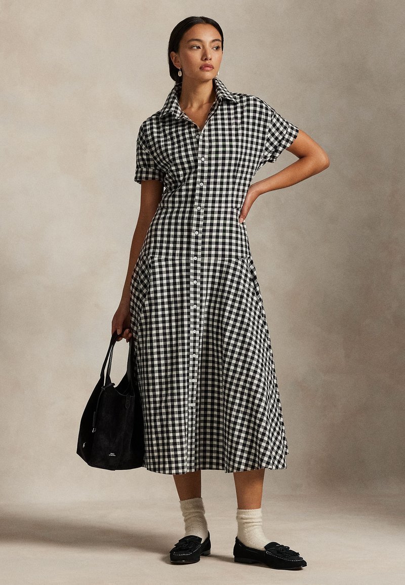 Robe mi-longue Maxime à motif vichy  bleu marine et blanc est boutonnée sur le devant et présente une encolure en V.