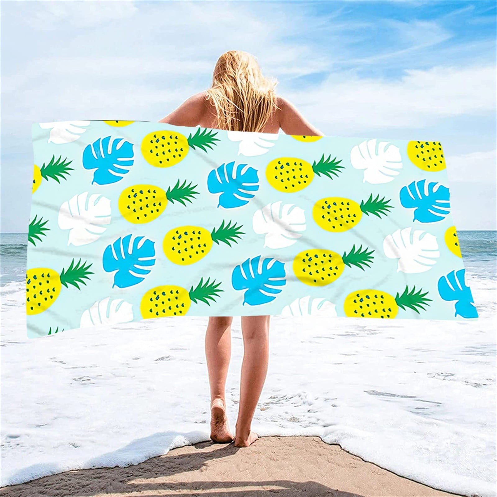  serviette de plage en microfibre au motif tropical imprimé d'ananas jaunes et de feuilles de monstera bleues et blanches sur fond bleu clair.