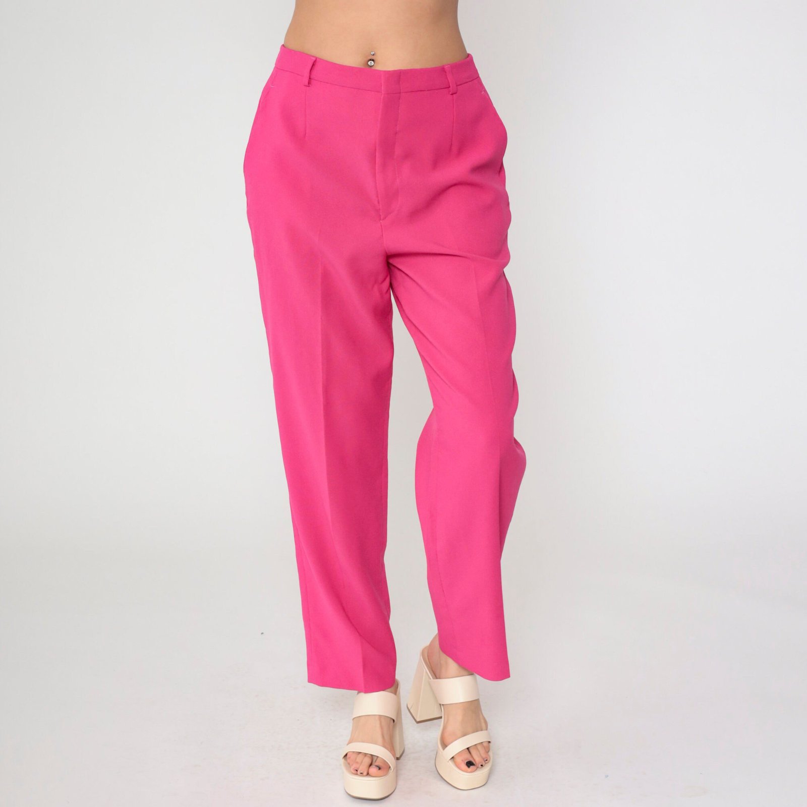 Pantalon rose fuchsia semble être un modèle de chez United Colors of Benetton. Il présente une coupe droite ou légèrement fuselée avec une taille haute classique, typique des collections de prêt-à-porter de la marque.