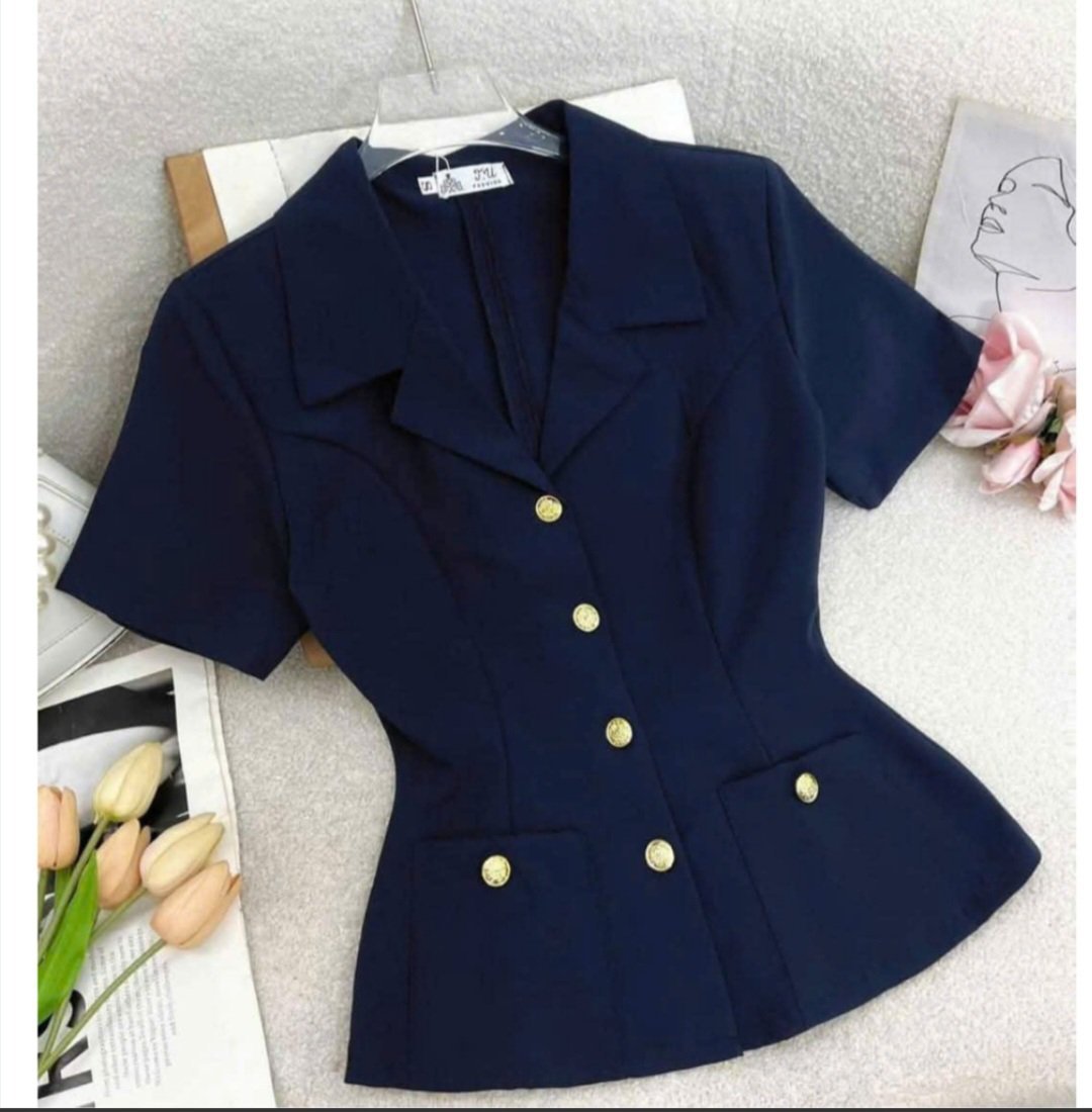 Un blazer à manches courtes pour femme, doté de boutons métalliques apparents.