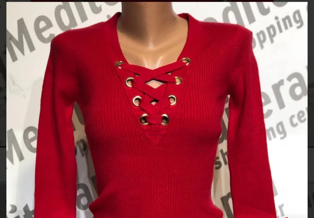 Un haut rouge à manches longues avec un laçage au niveau du décolleté de la marque Amisu
