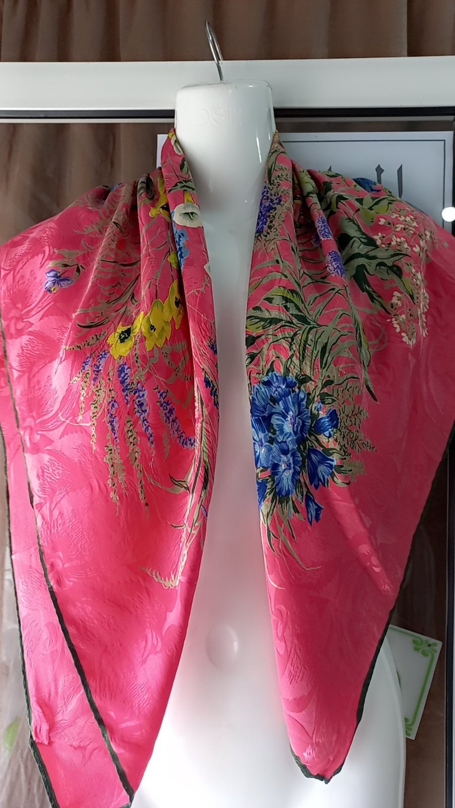 Un foulard ou une étole en soie de la marque Gianni Versace, caractérisé par un motif floral vibrant sur fond rose.