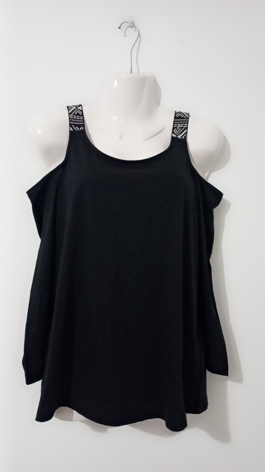 Pull noir à épaules dénudées, élégamment agrémenté de bretelles à motifs géométriques contrastés.    